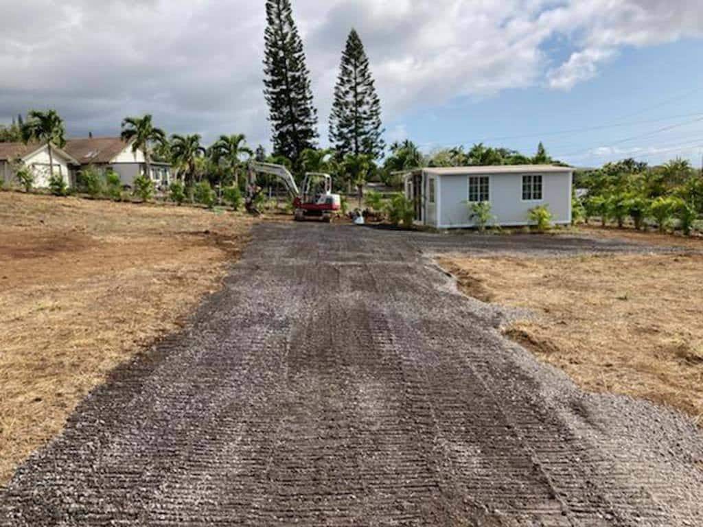 Hawaii excavators and landscapers installing driveway with aggregate and palm shrub landscaping near kona.