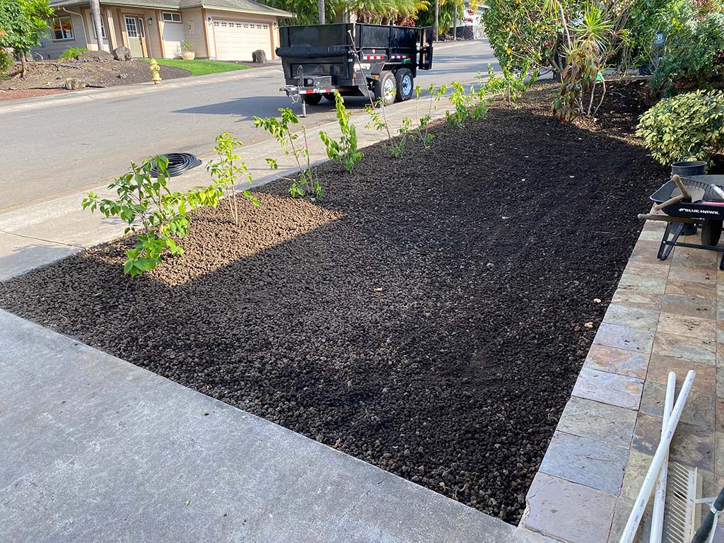 Black and red cinder spreading during landscaping, Hawaii. Topsoil delivery provided by big island landscape company.