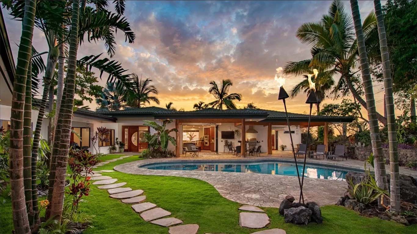 Image of the backyard of a house with pool and palm trees on the island of Hawaii. Landscaping services help maintain palms and local trees and hedges like this. Kailua-Kona landscape design, installation and yard maintenance, Big Island Hawaii.