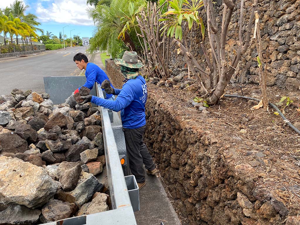 Kailua-Kona landscapers placing rocks on a rock wall landscape, Kona Hawaii.