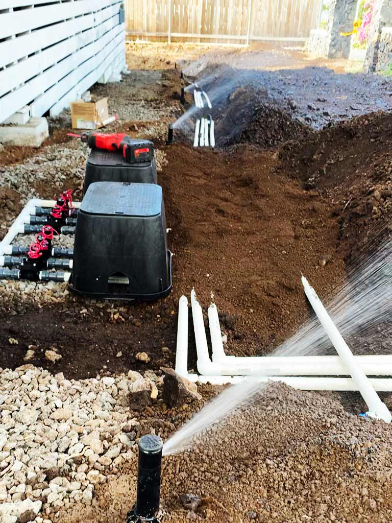 Underground sprinkler system installation, Hawaii. Irrigation such as sprinklers helps reduce monthly yard maintenance.