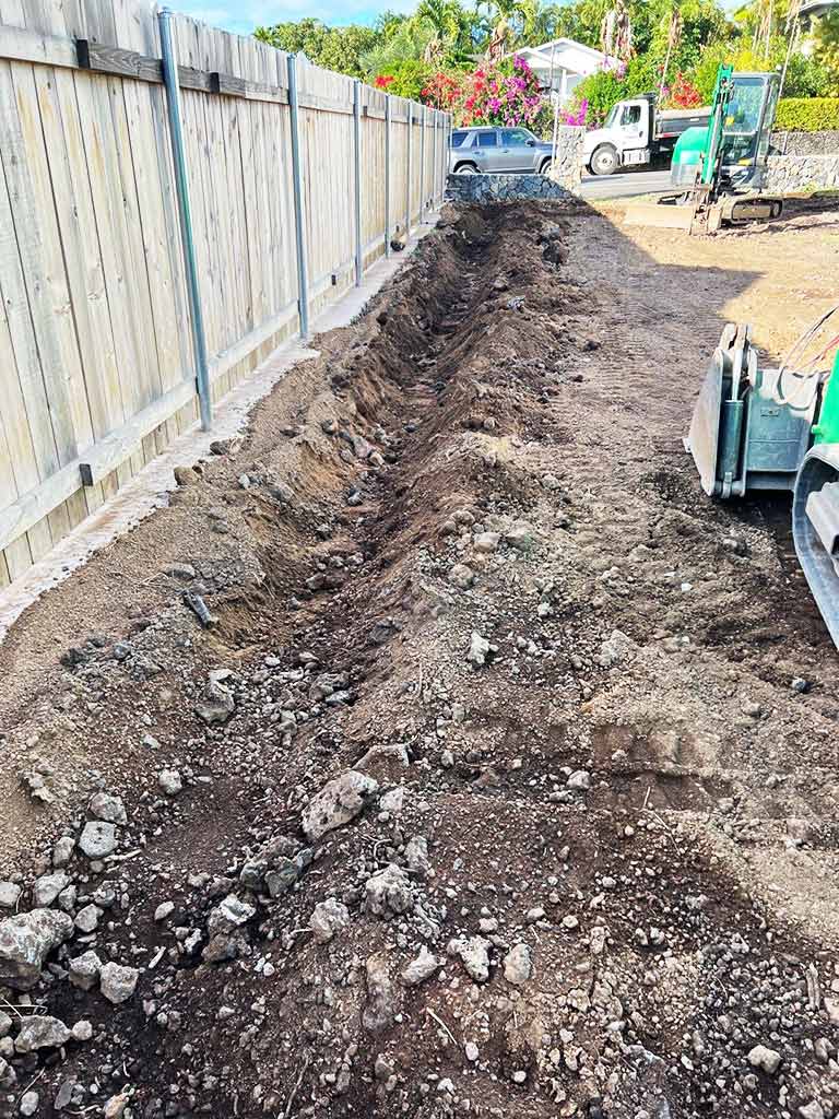 Excavator digging a trench for a backyard sprinkler system.