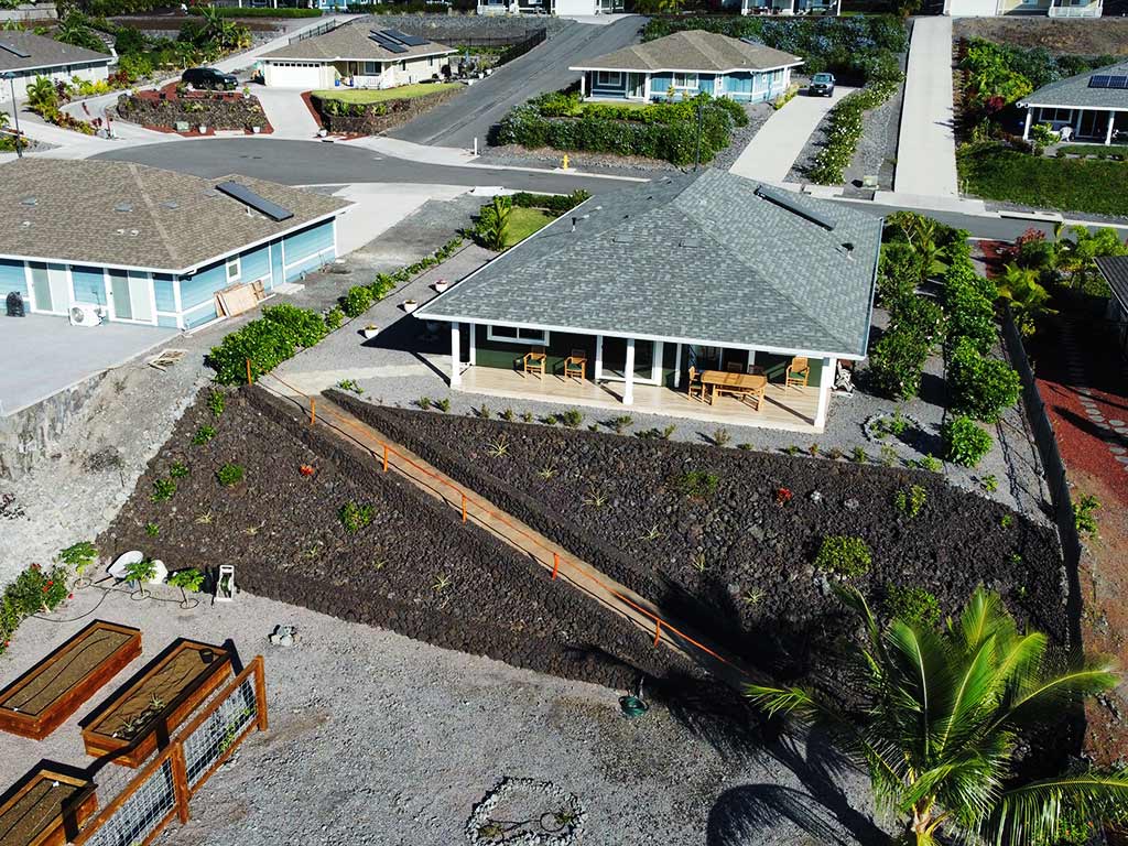 Seen from above this completed Hawaii landscape includes a lava rock wall, organic garden boxes, and a lilikoi fence.