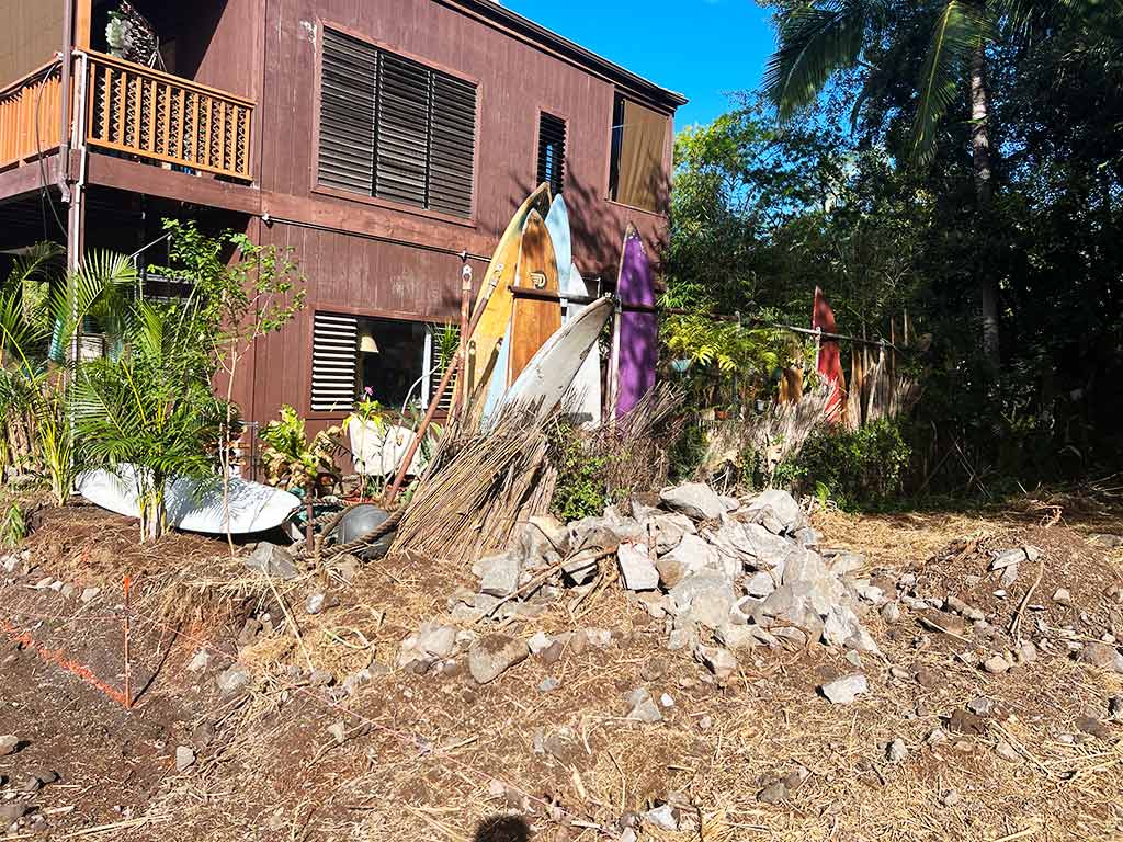 Surfboards and other debris line the edge of the house prior to the landscape clean-up, Kailua-Kona.