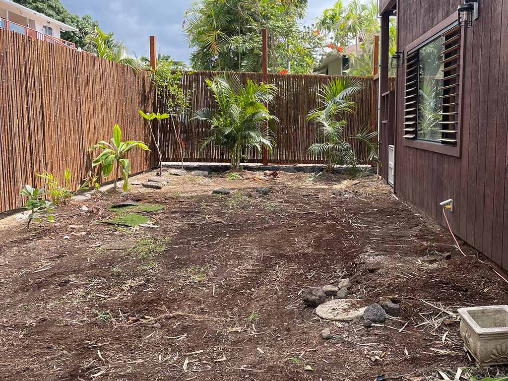 Landscapers level the topsoil and clean up the outdoor space prior to re-landscaping this backyard.