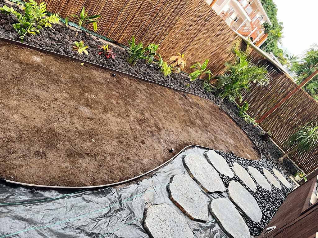 A weed barrier is installed under the lava rock and river rock flowerbed.