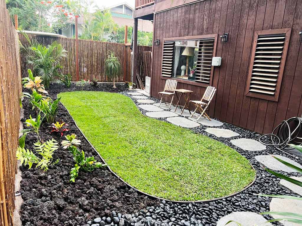 Finished lava rock flowerbeds surround a central turf area.