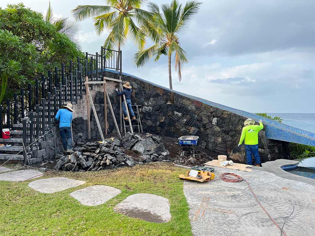 The rock wall building crew installs lava rock on the side of the slide.