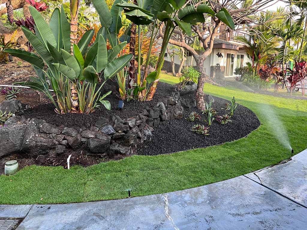 Lava rock is used as an aggregate ground cover for a flowerbed.